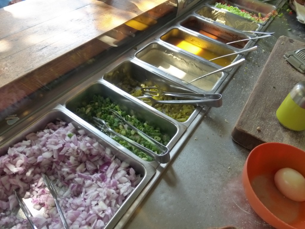Balcão refrigerado com os vegetais e molhos usados na preparação do sabich