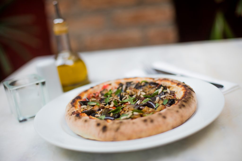 A La Siciliana leva molho de tomate fresco, a caponata da casa (feita com berinjela, salsão, tomate, pinhole e azeitona preta) e sementes de girassol que são salpicadas sobre a cobertura antes da pizza ir à mesa